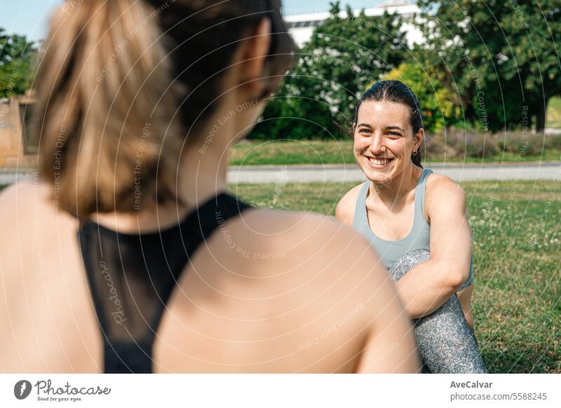 University friends resting on the campus grass while stretching to avoid injury after training. sports fitness person young lifestyle exercising women female