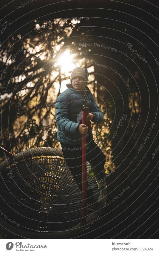 A boy on a net swing against the light Authentic Emotions Life Outdoors Tourism mountains Switzerland lenzerheide Autumn Winter Happiness Child