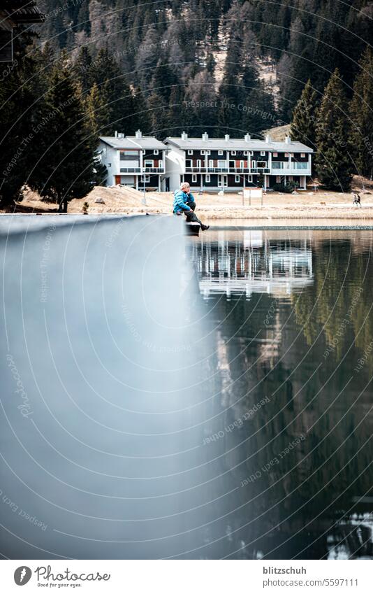 A boy sits on a jetty by the lake Lake November Boy (child) Infancy Family & Relations Friendship Child Happiness mountain lake Winter Autumn lenzerheide