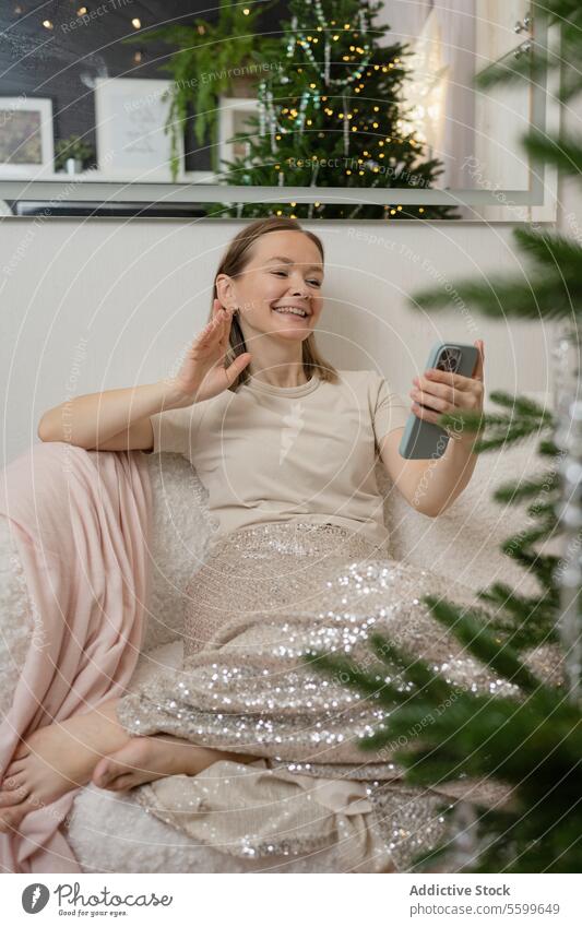 Woman relaxing at home during the festive season woman christmas sofa smiling remote tree lounge comfortable peaceful moment holiday decoration leisure joyful