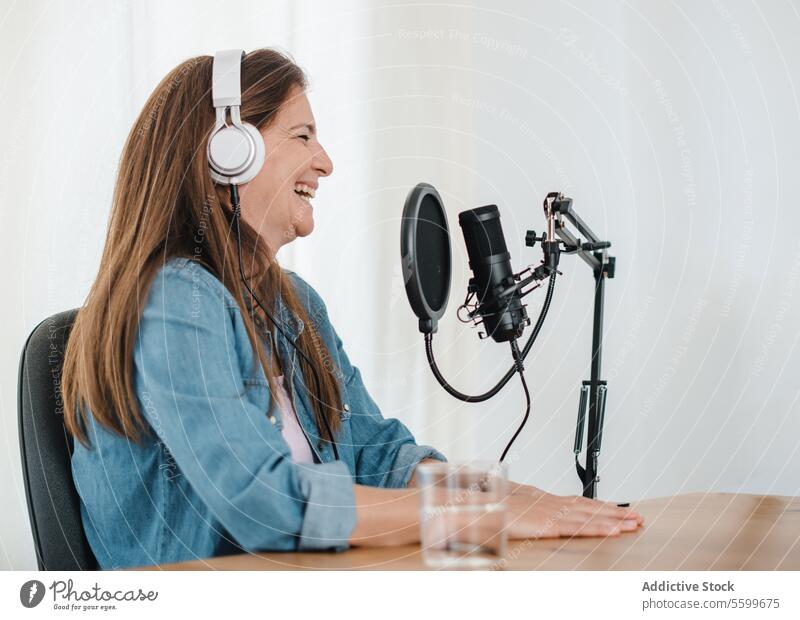 Cheerful woman in headphones recording podcast talk laugh having fun cheerful microphone broadcast female radio studio host speak content modern device announce