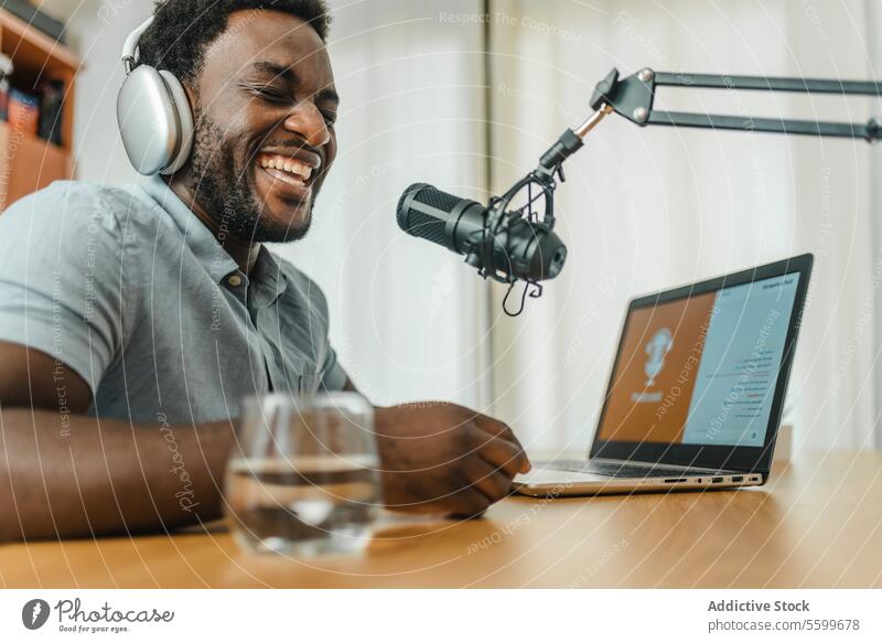 Black man in headphones recording podcast and laughing mic studio excited host radio having fun male ethnic black african american device headset audio sit work