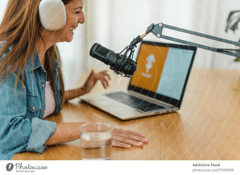 Woman in headphones recording podcast woman broadcast browsing laptop smile radio host microphone female talk speak sound studio content internet positive using