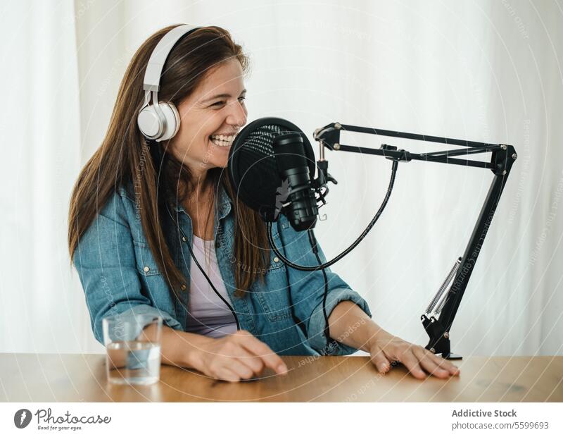 Happy woman recording podcast and laughing microphone having fun happy radio host live female broadcast studio speak talk smile headphones glad sit delight
