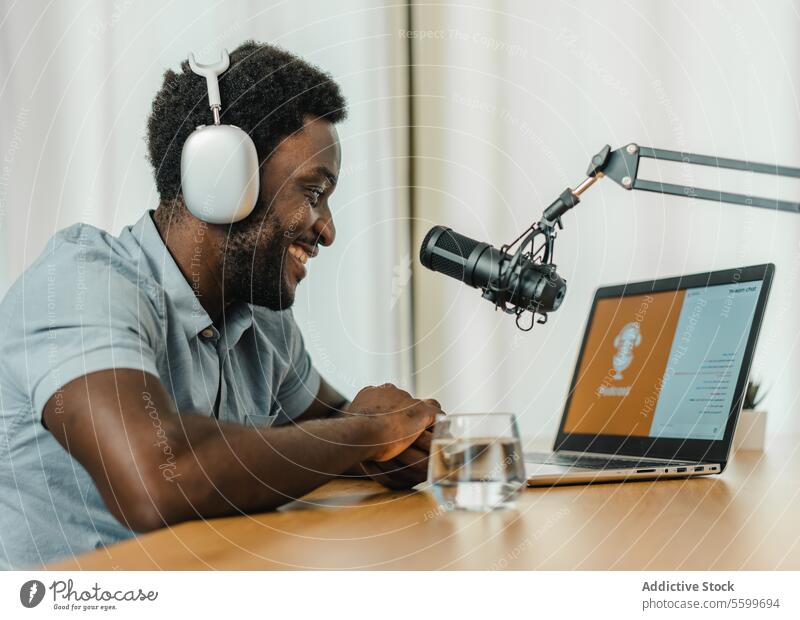 Smiling black man using laptop and recording podcast studio broadcast prepare smile microphone headphones male ethnic african american device work internet