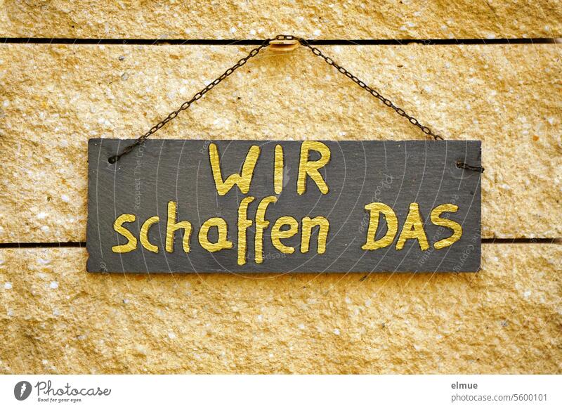 !Trash! 2023 I a black sign with golden lettering " WIR schaffen DAS " hangs on a stone wall we will make it Promise Optimism create Kitsch Target Doubt Future