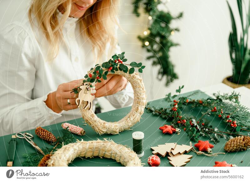 Woman decorating Christmas wreath at home occasion unrecognizable sparkle magic atmosphere present ornament shiny festive from above event celebrate indoors