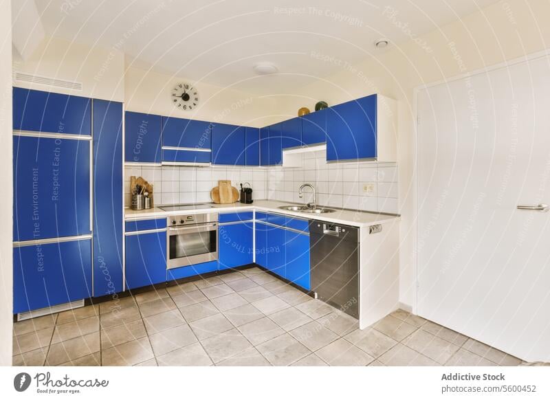 Blue kitchen with cabinets and modern appliances blue utensil clock induction microwave dishwasher sink faucet interior house contemporary white wall floor