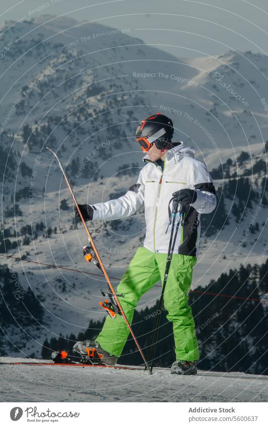 Skier preparing for descent in Swiss Alps skier swiss alps snow mountain slope ski gear white jacket green pants winter sport snow-capped peak alpine scenic