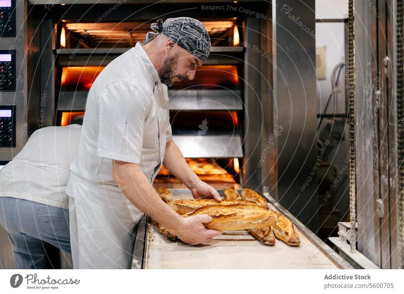 Baker picking bread from the conveyor belt man baker equipment bakery automation industrial tray food technology business product factory production industry