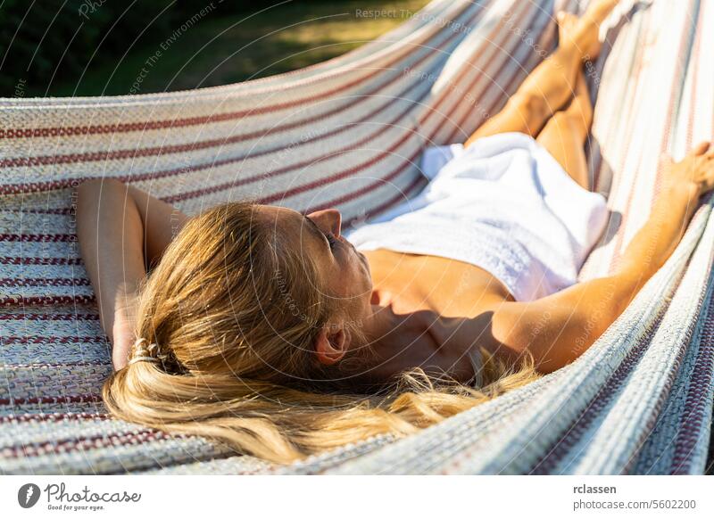 young woman relaxing in a hammock outdoor in spa resort hotel finnish sauna towel thermal bathrobe beauty body treatment skin health clean girl care skincare
