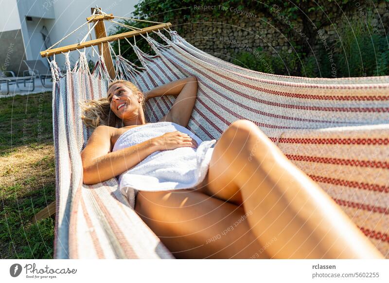 happy woman is relaxing in spa and wellness center on a hammock outdoor. Beauty treatment concept image hotel finnish sauna towel thermal bathrobe beauty body