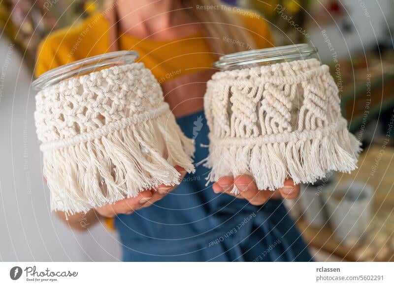 Close-up of hands holding macrame decorated glass jars decorated jars close-up crafting diy handmade decoration macrame decoration texture creative art hobby
