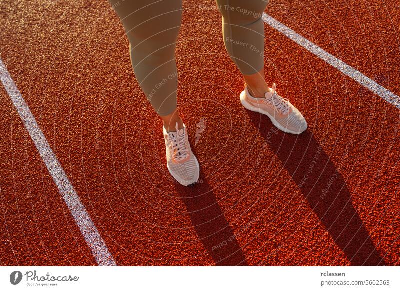 Close-up of female athlete's legs on starting line of running track close-up sportswear running shoes fitness preparation track and field competition