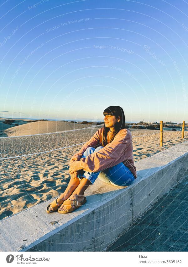 Woman sitting on a stone wall in front of the dunes of Maspalomas and looking into the sun Sun Gran Canaria Face sunshine vacation Sit Sand Nature Summer Sky