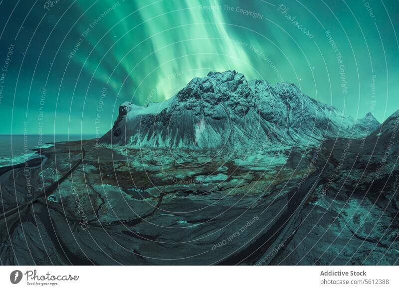 Majestic Northern Lights Over Snowy Icelandic Peak aurora borealis northern lights iceland mountain snow winter night sky nature natural wonder landscape green