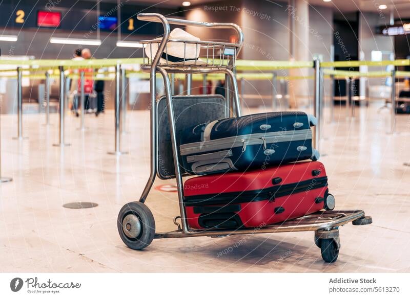 Trolley with suitcase and hat at airport trolley terminal colorful steel modern flight trip blurred background luggage vacation holiday departure arrival floor