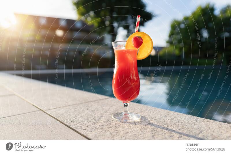 refreshing red cocktail garnished with a strawberry and orange slice by a poolside at sunset wellness spa hotel red drink strawberry garnish summer beverage