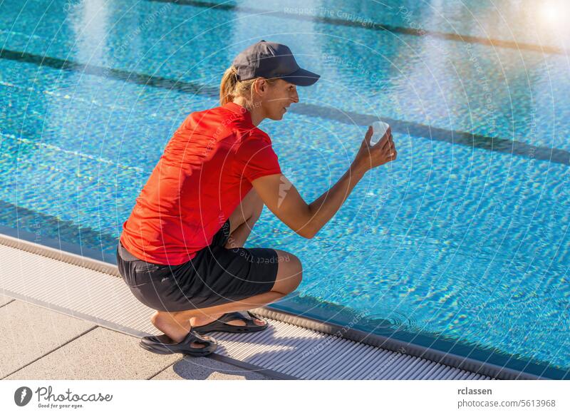 Woman squatting by a pool holding a clear container to examine water quality in a spa wellness resort chlorine measure sample hygiene summer investigate