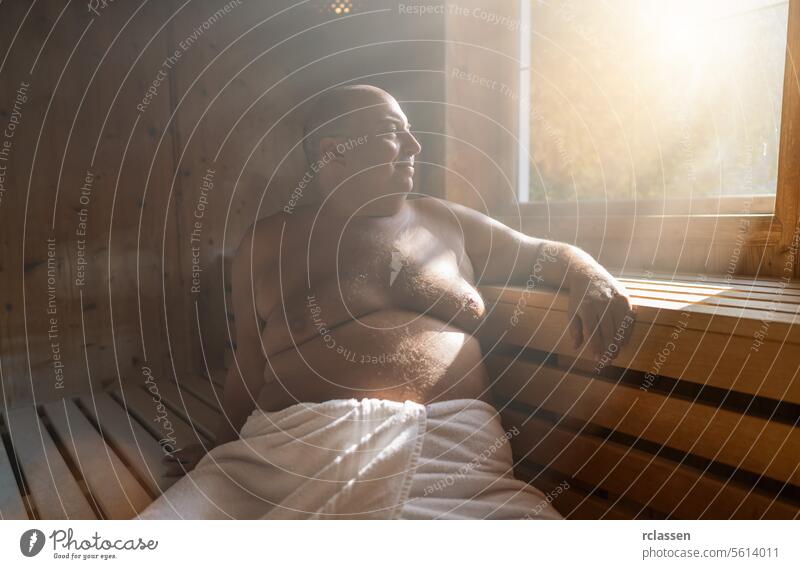 Content man relaxing in a finnish sauna, with sunlight streaming through the window. wellness spa resort hotel sweat finland man in sauna smiling relaxation