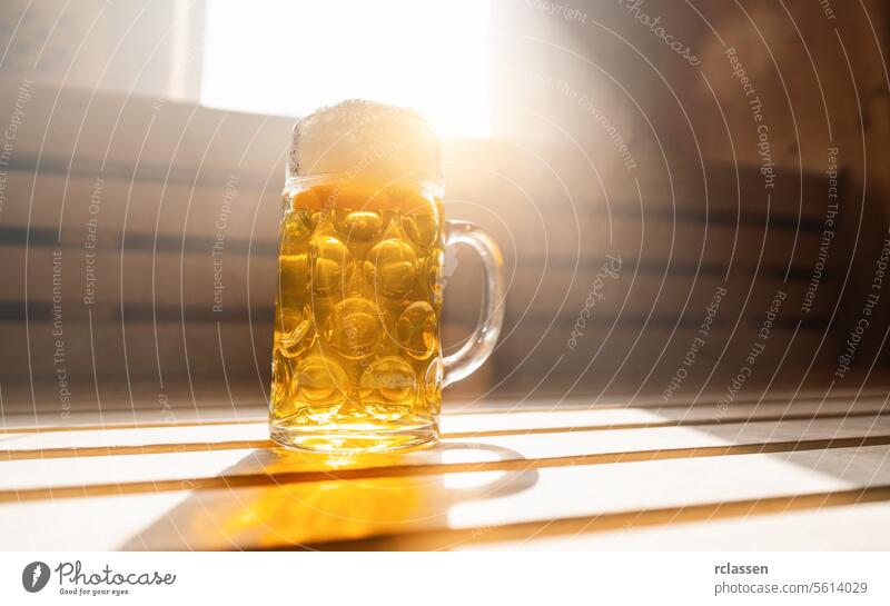 beer mug with frothy beer rest on a ledge in a finnish sauna, catching sunlight. spa and wellness concept image interior health hotel friends window alcohol