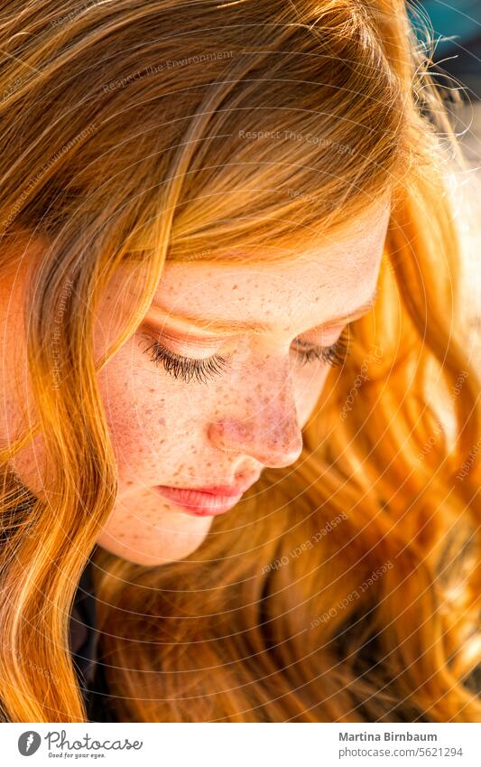 Beautiful red haired young woman looking down long hair caucasian freckles human face portrait female beautiful happy beauty people close up happiness positive