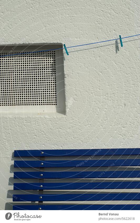 Blue bench and line in front of a white wall Bench Wall (building) House (Residential Structure) Wall (barrier) Window clothesline clothespin Exterior shot