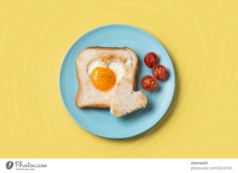 Valentine's Day breakfast with egg with tomatoes, heart shaped and toast bread on yellow background blue concept food fried healthy isolated love plate