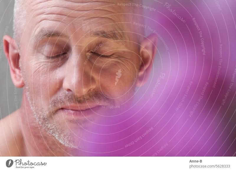 let's talk about feelings , portrait of an attractive man around 40 with closed eyes , in the foreground a pink blurred flower Perception relaxation Odor