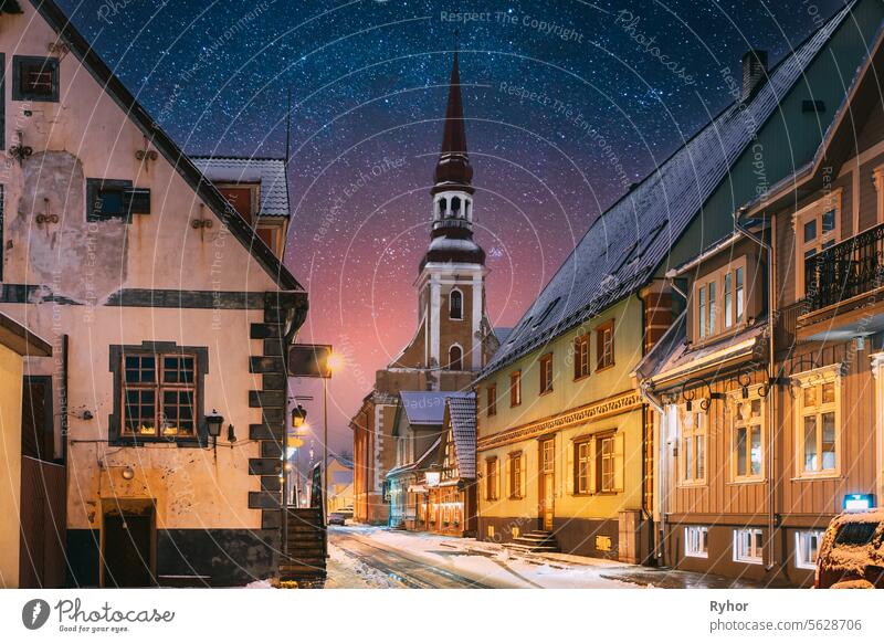 Parnu, Estonia. Night View Of Kuninga Street With Old Houses In Evening Night Illuminations. Amazing Bold Bright Blue Starry Sky Gradient. View Of Lutheran Church Of St. Elizabeth On Background