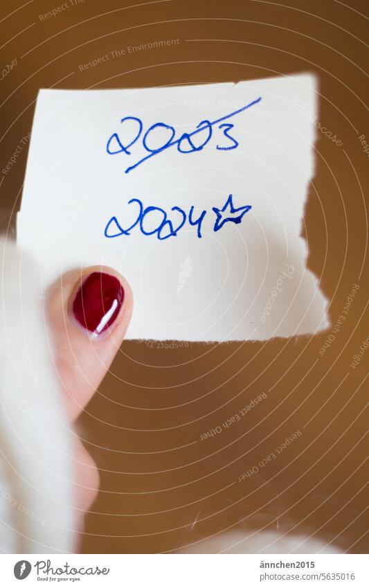 A Piece Of Paper With The Dates 2023 And 2024 Is Held By A Finger With   5635016 A Piece Of Paper With The Dates 2023 And 2024 Is Held By A Finger With A Red Painted Nail Photocase Stock Photo Large 