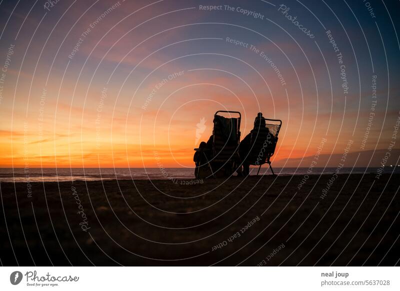 Silhouette of two people on camping chairs in front of an evening sky by the sea Sunset Ocean Beach Evening Dusk Couple boyfriend romantic togetherness