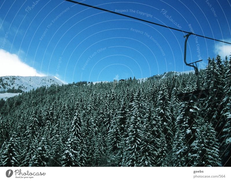 liftblick01 Winter Mountain Alps Nature Chair lift Skilift chair Mountain forest Winter forest Coniferous forest Ski resort Blue sky Copy Space top Empty