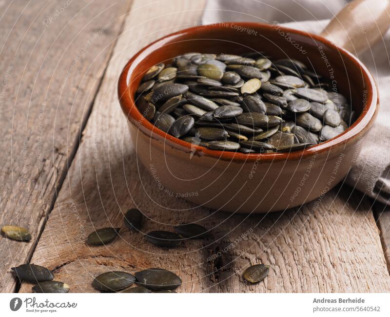Tasty organic pumpkin seeds in a ceramic bowl on a wooden kitchen table vegan energy vitamin green uncooked nutritious vegetable wooden background raw nutrition