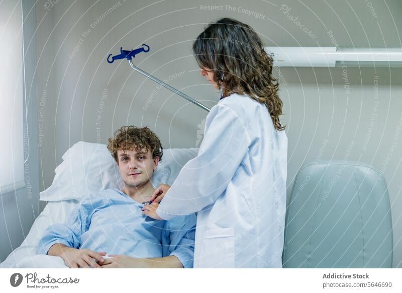 Crop physician examining patient lying on bed with stethoscope in clinic man doctor nurse check up examine hospital uniform health care diagnostic specialist