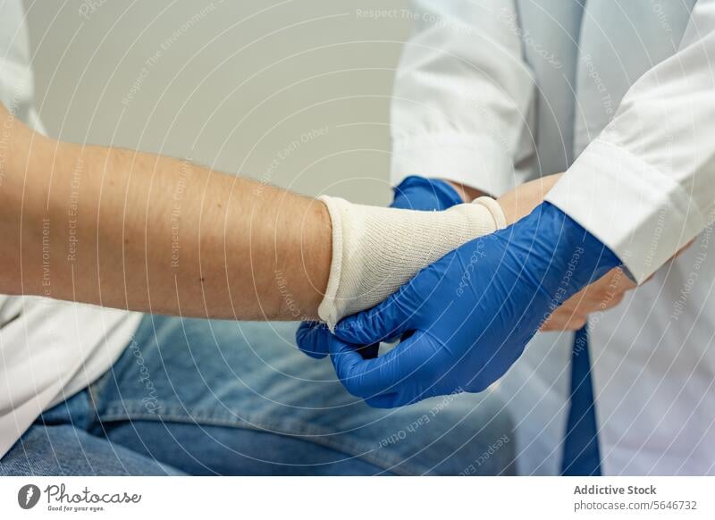 Crop doctor putting on protective elastic band in hands of patient at clinic glove health care hospital specialist uniform professional medic medicine put on