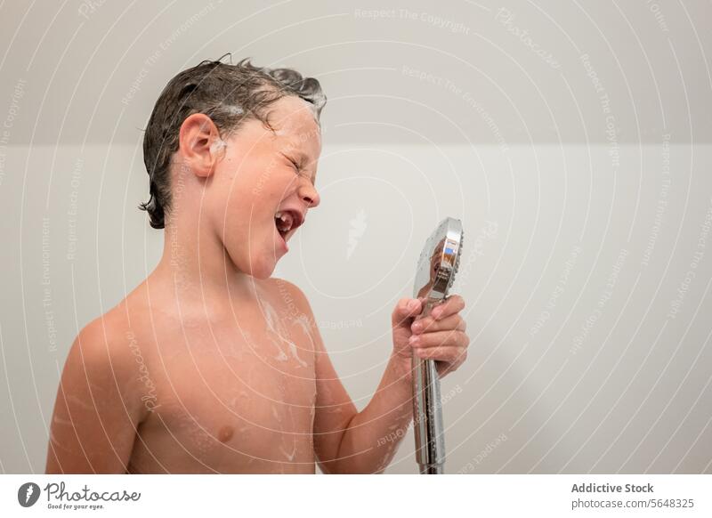 Boy holding hand shower while taking bath in bathroom boy portrait sing pretend dream child shampoo cute foam hygiene childhood having fun wash kid routine care