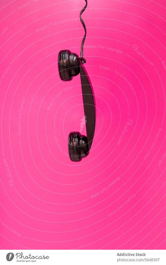 Hanging Receiver on Pink Background receiver hanging telephone black pink background disconnected communication interruption solitary cord vivid symbol vintage