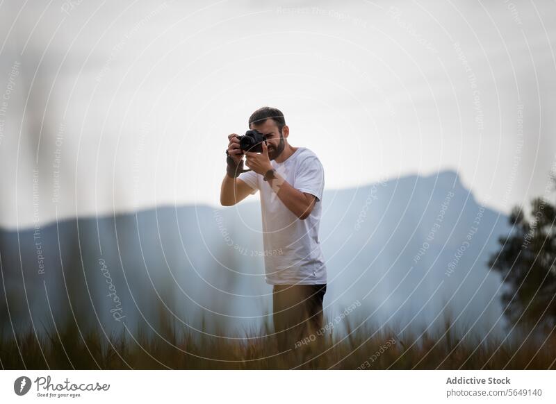 Man capturing nature in national park on grassy meadow Tourist Camera Take Photo Nature National Park Photographer Meadow Leisure Vacation Using Recreation