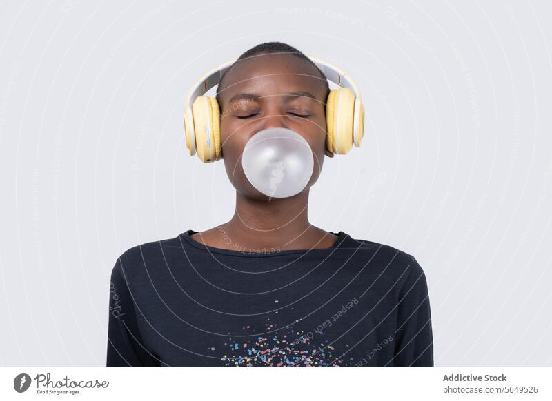 Contented black woman witj eyes closed listening music while blowing bubble gum Woman Headphones Music Bubble Gum Blow Fashion Enjoy Model Eyes Closed Happy