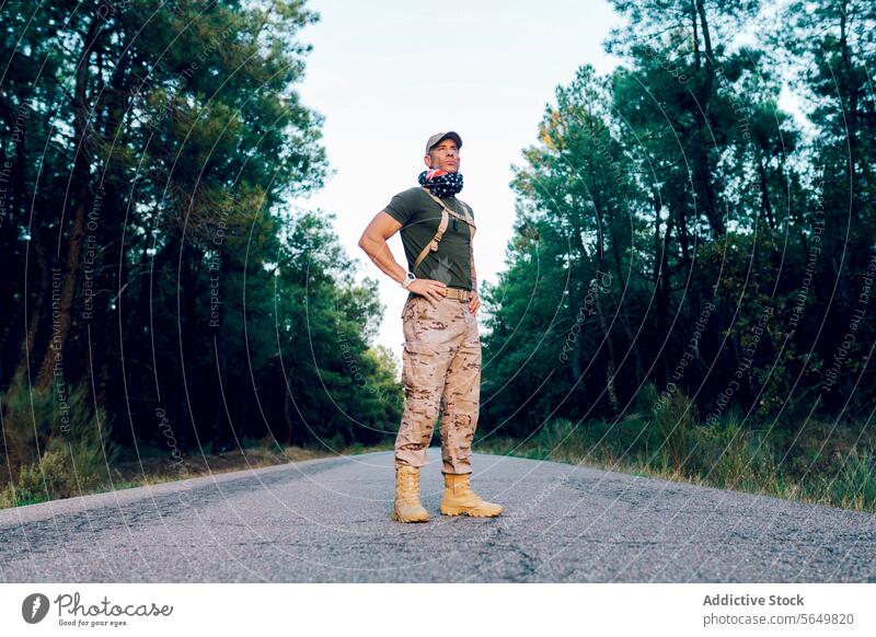 Low angle of Male commando with American flag wrapped around neck and looking away with pride while standing on road soldier military american confident green
