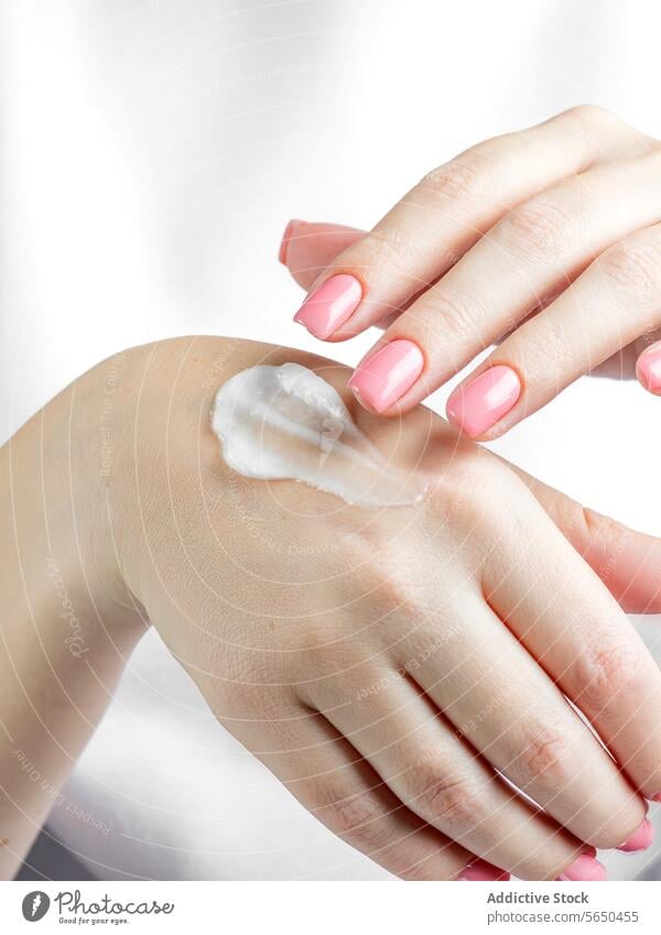 Woman applying lotion on her hands for skincare routine cream moisturizer woman nail polish beauty close-up product hydration health wellness female pampering
