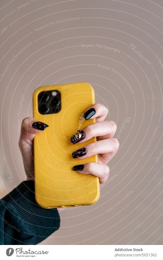 Crop woman with black nail art holding cellphone hand smartphone manicure nail polish creative yellow style device gadget modern mobile female paint body part