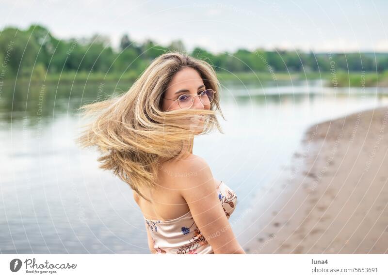 happy young woman with flowing hair stands by the river Woman fortunate Blow Disheveled youthful Laughter Wind sensual windy daintily pretty Single cheerful