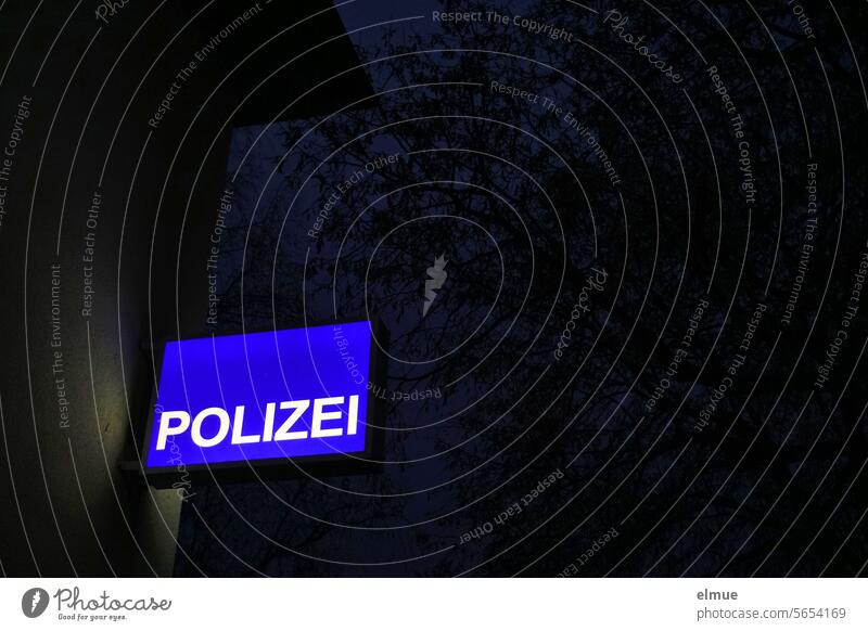 blue illuminated sign with POLIZEI on a house wall in the dark Police Force light shield advertising sign Safety Police Station awake police station Lightbox