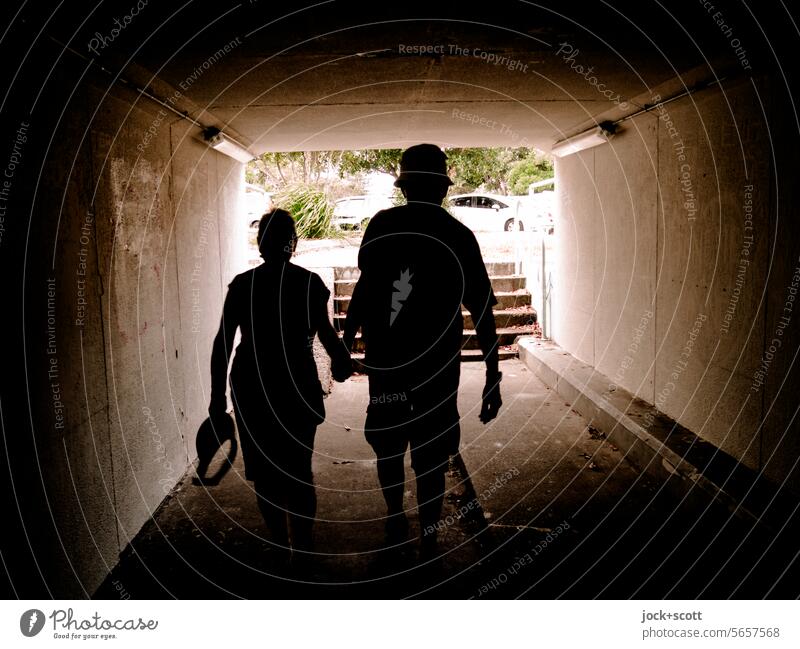 Shortcut through the pedestrian tunnel Lanes & trails Underpass Architecture Passage Couple Back-light Silhouette Tunnel vision Shadow Contrast Stairs Symmetry