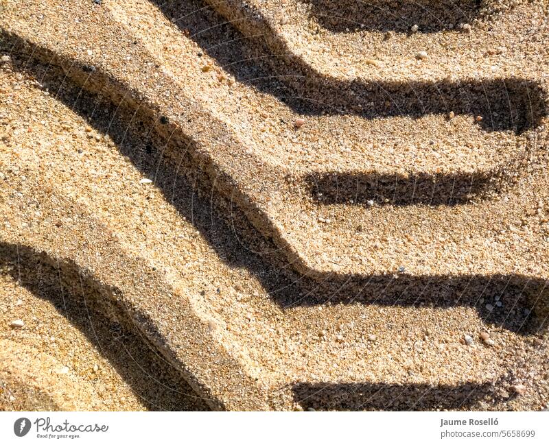 background of tractor wheels with curious shapes and embossed with shadows on the beach sand with wet ground truck transport land footprint desert