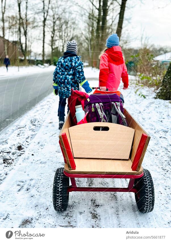 Going to school in winter | Two children pulling a handcart with school bags Winter Student pupil Schoolchild home way to school on the way home Satchel
