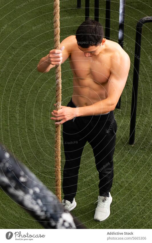 Shirtless sportsman adjusting rope before calisthenics workout climb prepare exercise training healthy lifestyle sports ground male young shirtless athlete gym
