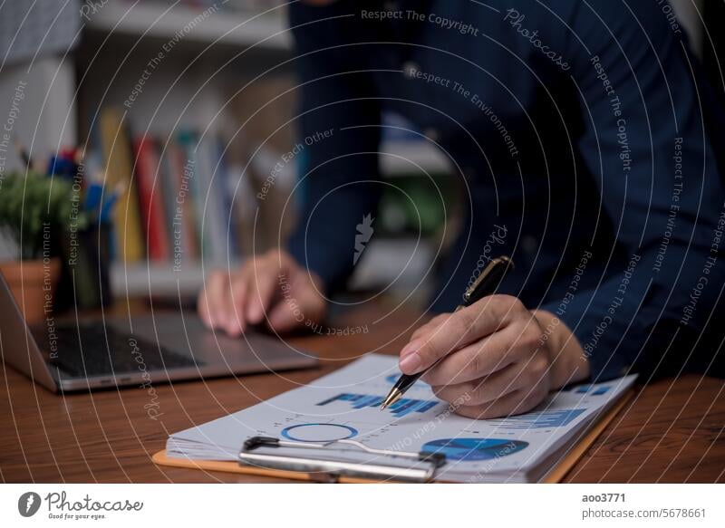 Businessman is using a laptop and pointing to a marketing graph working on analyzing financial report company documents, management report online accounting in the office.